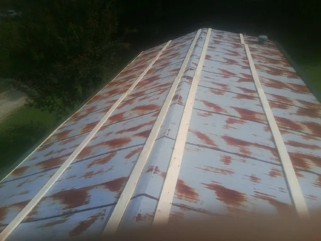 Rusted metal roof panels with new wood purlins before replacement — Storm Damage Roof Repair in Clay Center by Roofing Brothers