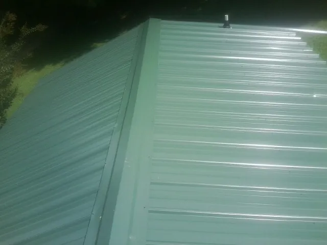 New green metal panels meeting at the ridge of a roof — Flat Roof Repair work by our crew in Clay Center