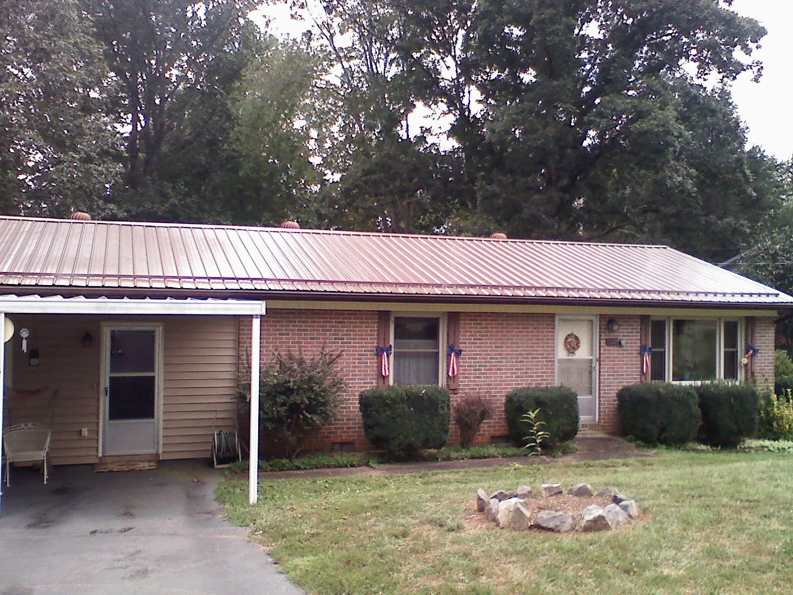 Bronze metal roof and carport on a brick ranch home — Roof Repair work by our crew in Clay Center
