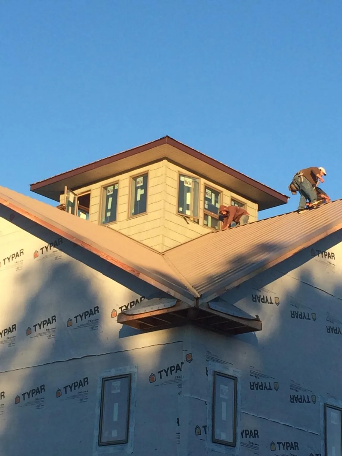 Roofers working around a rooftop cupola on a new metal roof at sunset — Roof Waterproofing in Clay Center by Roofing Brothers